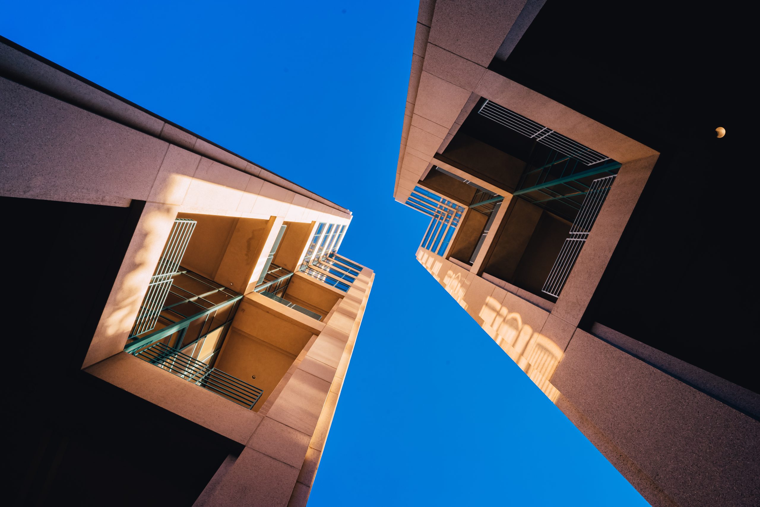 frog s eye view architectural twin buildings against clear blue sky scaled